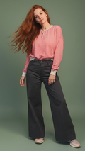 Modella capelli rossi stile casual etereo con pantalone grigio su sfondo verde salvia