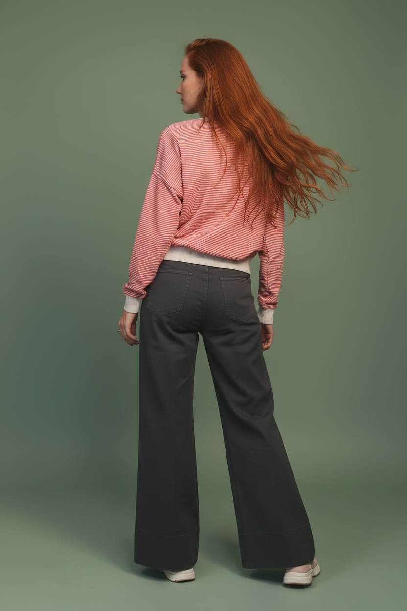 Modella di schiena capelli rossi con pantalone grigio su sfondo verde salvia